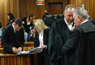 Oscar Pistorius, left talks to a member of his defense team in court on the second day of his trial at the high court in Pretoria, South Africa, Tuesday, March 4, 2014. Pistorius is charged with murder for the shooting death of his girlfriend, Reeva Steenkamp, on Valentines Day in 2013. (AP Photo/Antione de Ras, Pool)