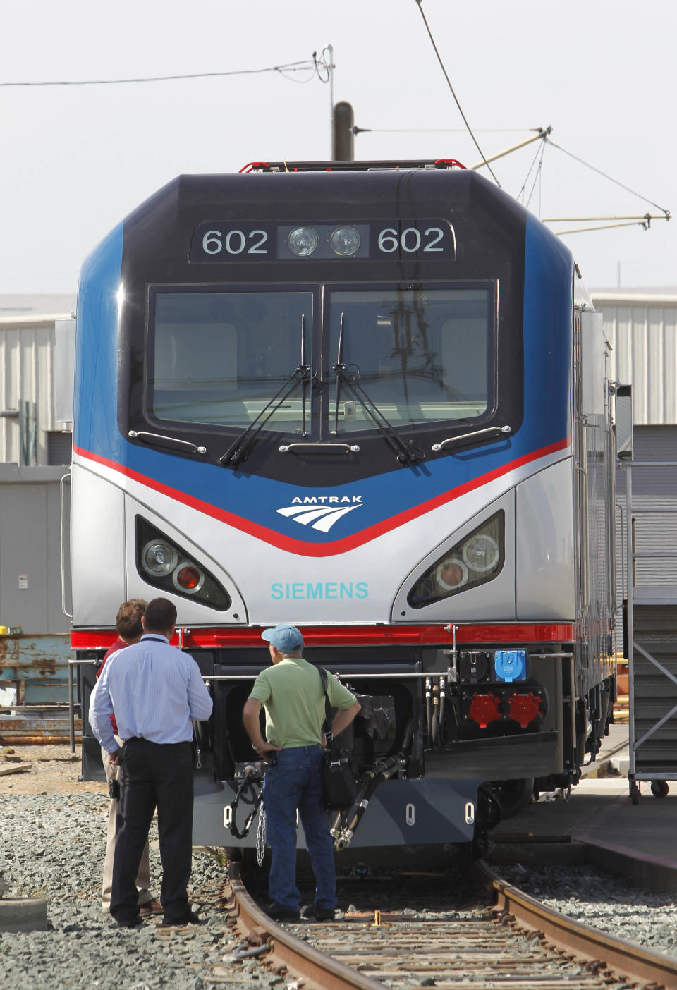 In this photo taken Saturday, May 11, 2013, Dave Ward, vice president of Locomotives for the Siemens Rail Systems, right, and Amtraks Phil Smith, left, and John Hines, center, look over one of the new Amtrak Cities Sprinter Locomotive built by Siemens in Sacramento, Calif. The new electric locomotive, one of three of 70 to be built, will run on the Northeast intercity rail lines and replace Amtrak locomotives that have been in service for 20 to 30 years.(AP Photo/Rich Pedroncelli)