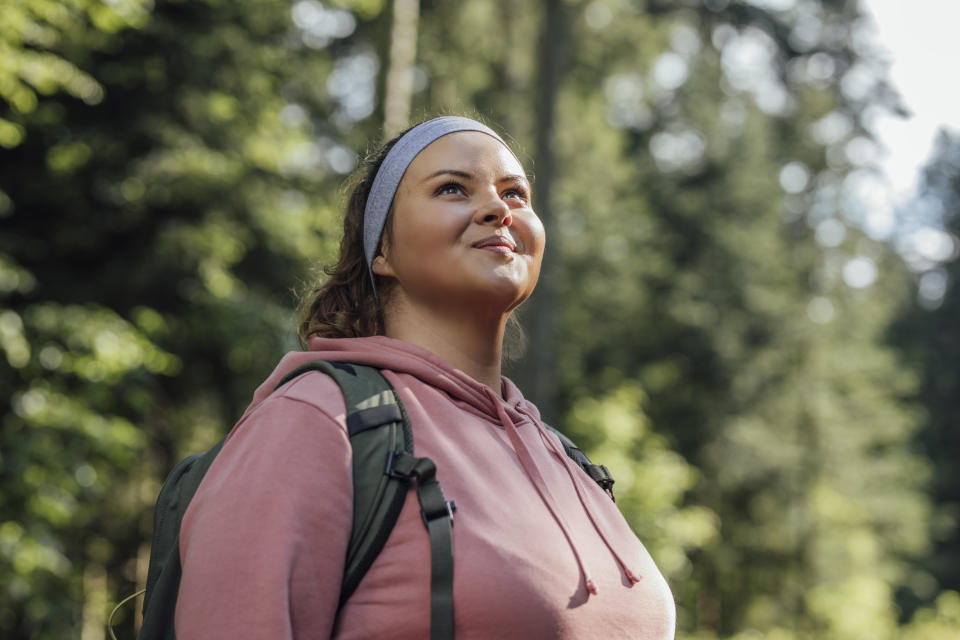 A woman in the forest looking up