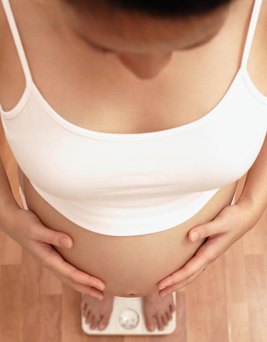 pregnant woman weighing herself on bathroom scale