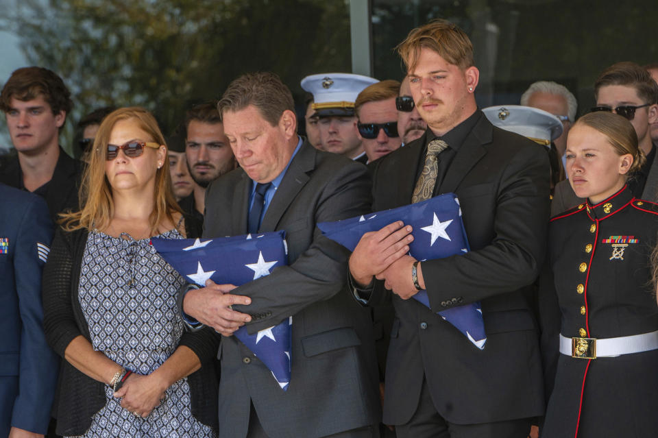 After the service for fallen Marine Sgt. Nicole Gee, her father Richard Herrera, center, and husband Jarod Gee, right, hold U.S. flags as her casket is moved to the hearse at Bayside Church Adventure Campus in Roseville, Calif., Saturday Sept. 18, 2021. Sgt. Gee lost her life, along with 12 other U.S. service members, in the bombing attack at the Kabul airport in Afghanistan on Aug. 26. (Renee C. Byer/The Sacramento Bee via AP)