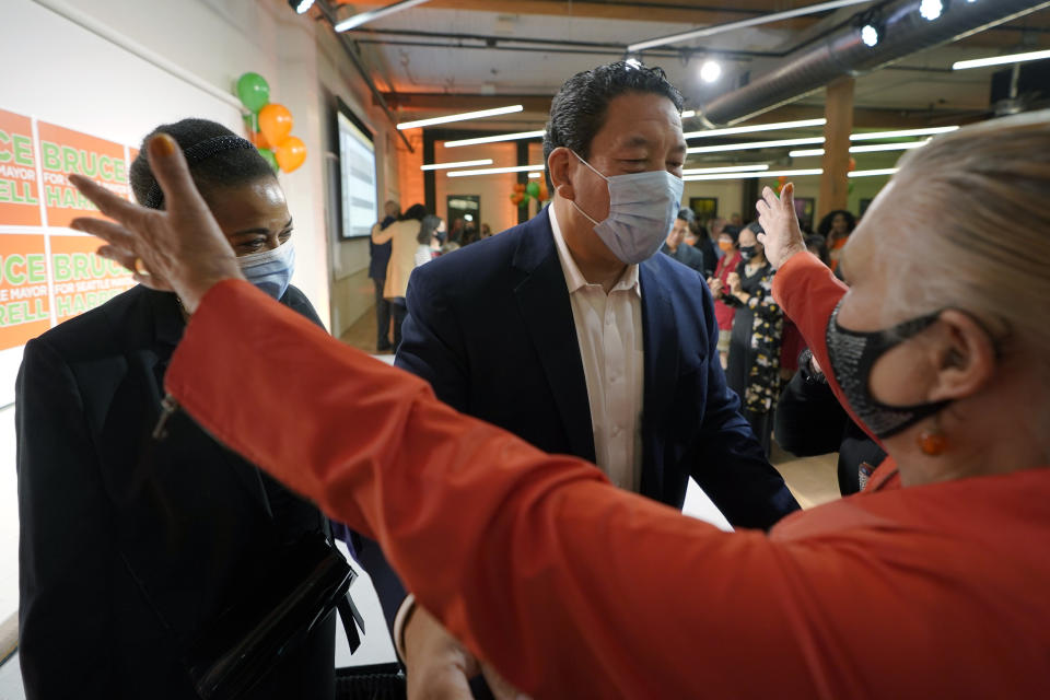 Bruce Harrell, center, who is running against Lorena Gonzalez in the race for mayor of Seattle, greets a supporter, right, as his wife, Joanne Harrell, left, looks on, Tuesday, Nov. 2, 2021, on election night in Seattle. (AP Photo/Ted S. Warren)