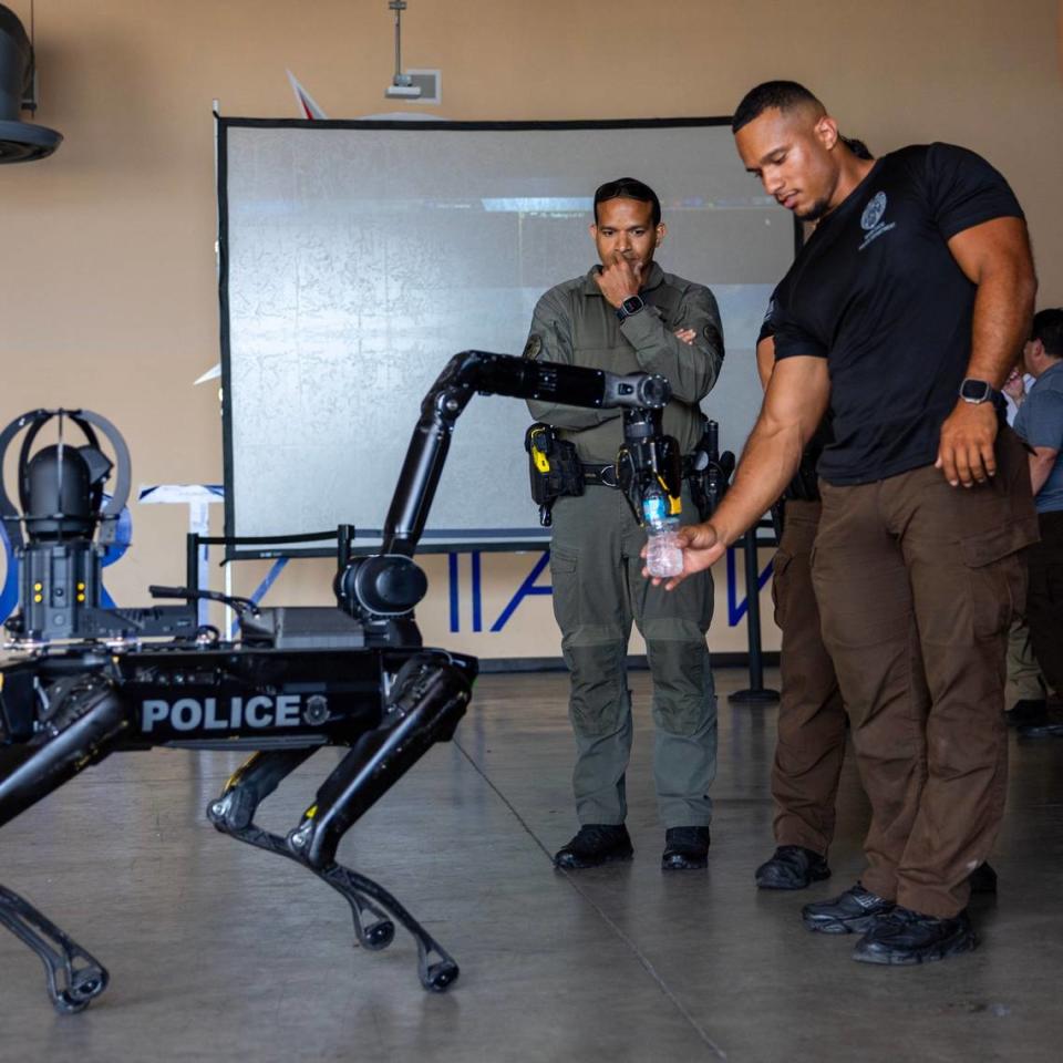 Officer J. Esteoan interacts with “Spot,” a robotic dog owned by Miami-Dade Police’s Special Response Team Department during a South Florida Public Safety Regional Assets in Action Demonstration showcasing an active threat response incident in Biscayne Bay as part of the annual 2024 National Homeland Security Conference at PortMiami, Terminal J on Wednesday, July 24, 2024, in Miami, Fla.