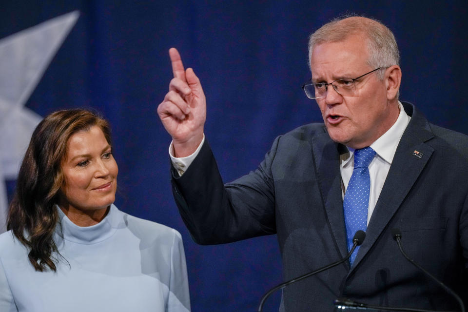 Australian Prime Minister Scott Morrison gestures as his wife Jenny watches as he addresses a Liberal Party function in Sydney, Australia, Saturday, May 21, 2022. Morrison has conceded defeat and has confirmed that he would hand over the leadership of the Liberal Party following his party's loss to Labor in today's federal election. (AP Photo/Mark Baker)