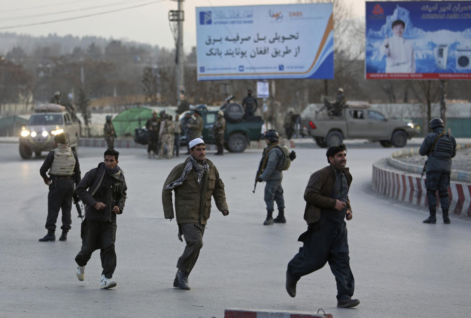 People run away from the site of a clash between insurgents and security forces in Kabul, Afghanistan, Monday, Dec. 24, 2018. Police have cordoned off the area in the east of the capital Kabul as they battle to gain control of the situation. (AP Photo/Rahmat Gul)