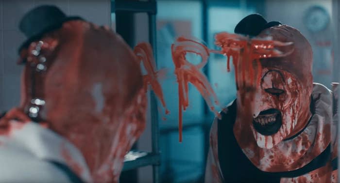A bloodied clown standing in front of a mirror with "Art" written across it (in blood)