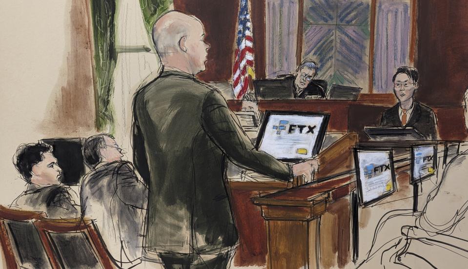 This courtroom sketch shows FTX co-founder Sam Bankman Fried, far left, listening as Assistant U.S. Attorney Nicholas Roos, center, questions co-founder of FTX Gary Wang, far right, during Bankman Fried's fraud trial, Friday, Oct. 6, 2023 in New York. (AP Photo/Elizabeth Williams)