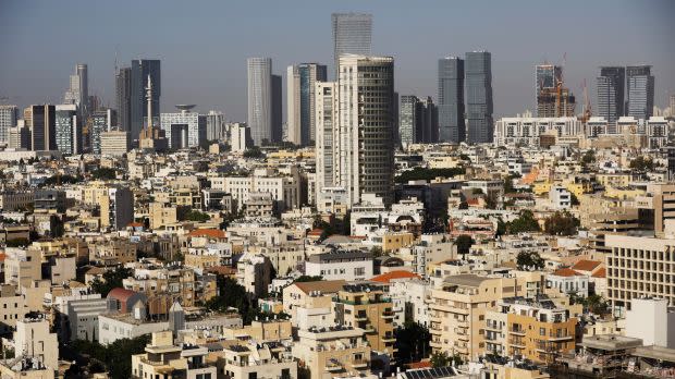 the skyline of Tel Aviv, Israel can be seen, showing highrise buildings in the distance, and shorter, light-colored multistory buildings in the foreground