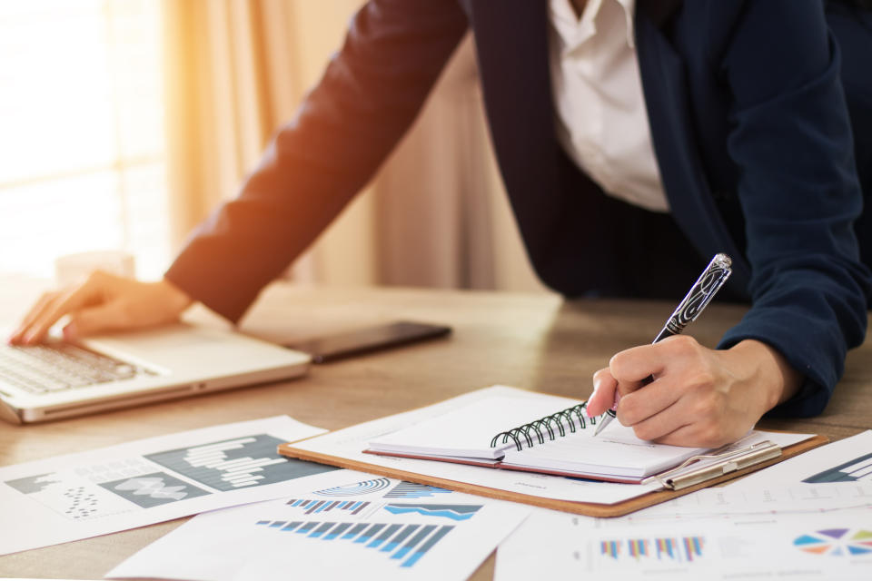 Hands of financial manager taking notes when working