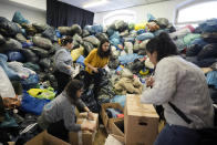 People sort and pack relief supplies in a packed room at a collection point of the Turkish community in Berlin, Germany, Tuesday, Feb. 7, 2023. Hundreds of members of Berlin's Turkish community flocked to a music school in the German capital to donate essential humanitarian supplies after the devastating earthquake that struck Turkey and Syria on Monday. (AP Photo/Markus Schreiber)