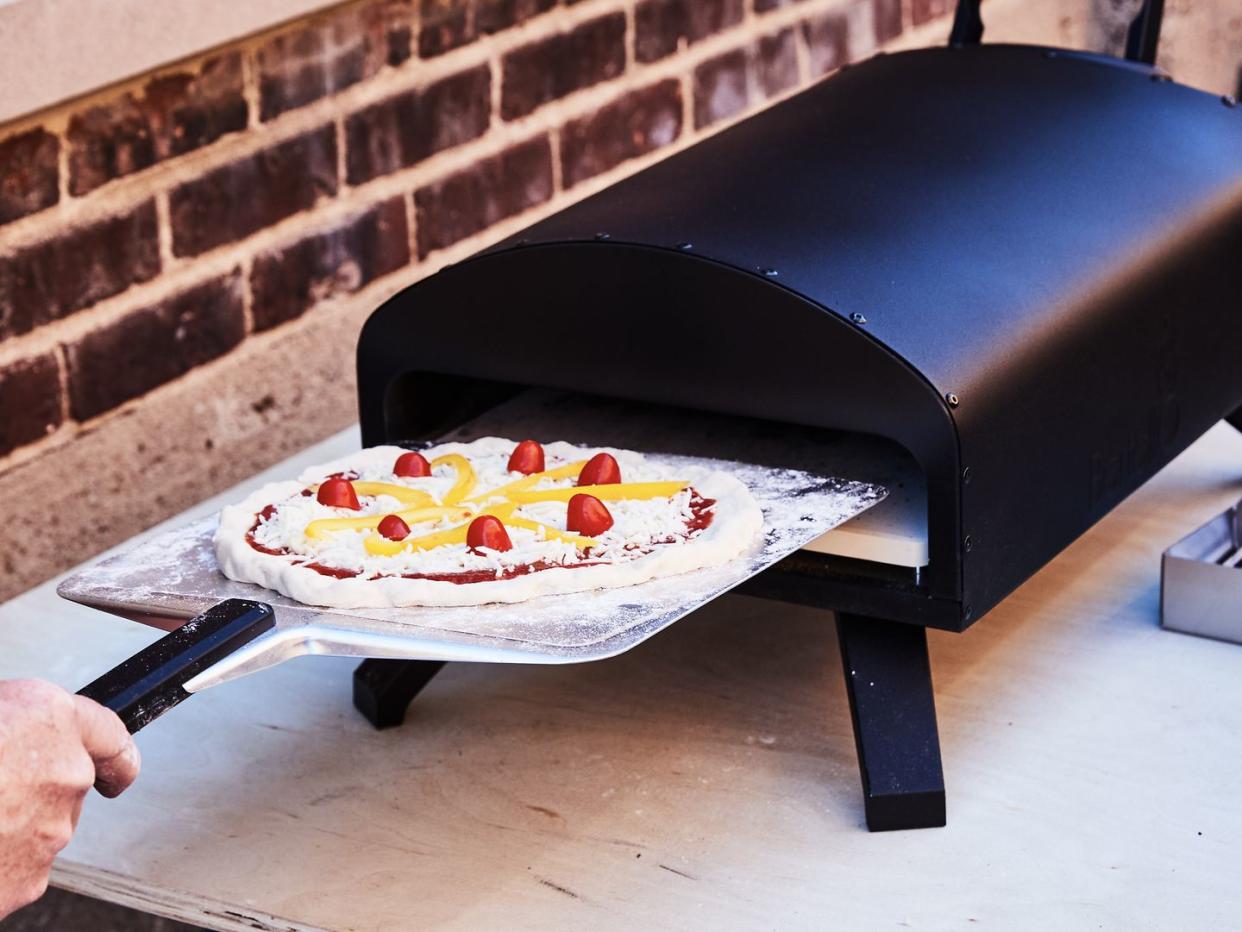 putting pizza in a bertello pizza oven