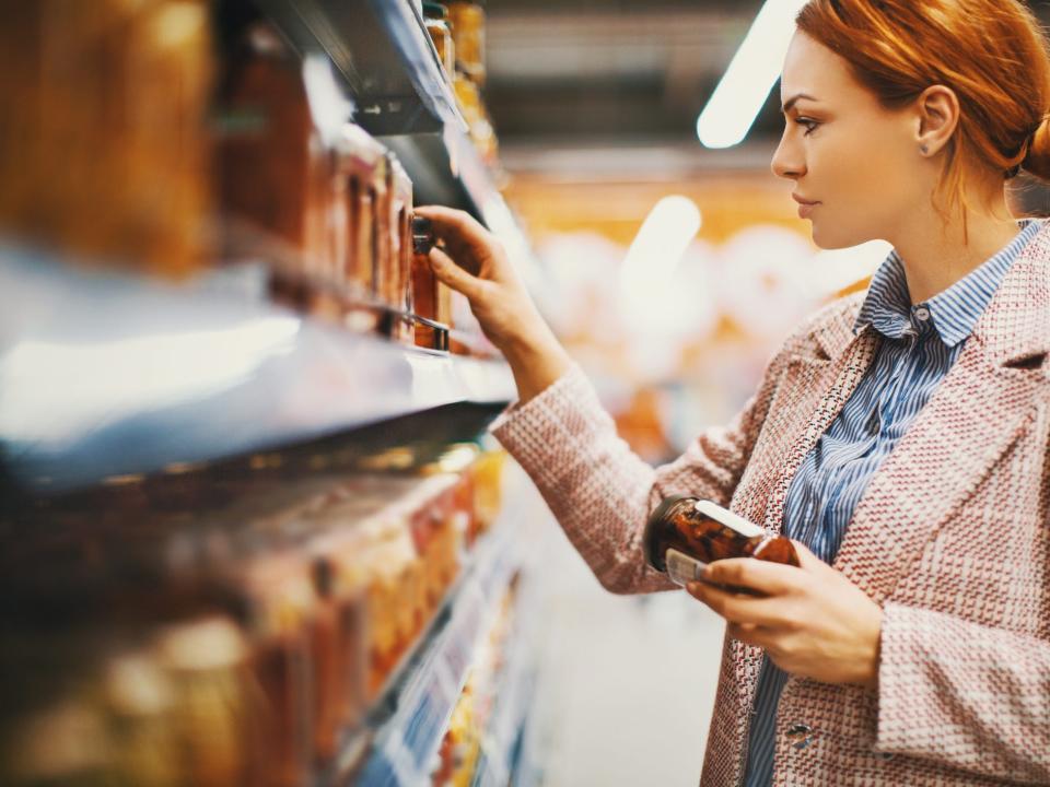 a person in a grocery store aisle reading a food label