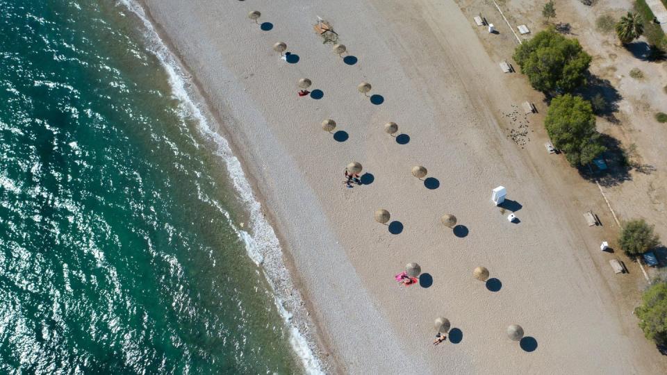 An einem Strand südlich von Athen stehen Sonnenschirme für Strandbesucher bereit. Wegen sinkender Corona-Infektionszahlen streicht die Bundesregierung am Sonntag Griechenland, fast ganz Frankreich, die Schweiz und Belgien von der Liste der Risikogebiete.