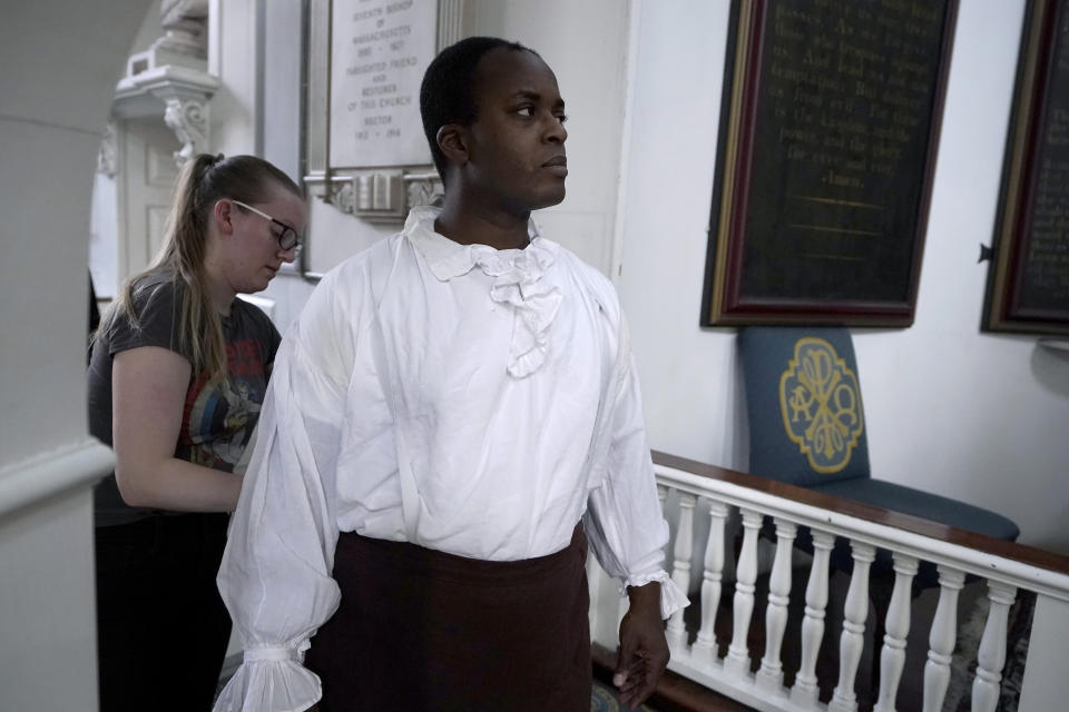 Actor Nathan Johnson, in the role of Cato, front, receives assistance with his costume from costume designer Christina Beam, behind left, before the start of a dress rehearsal of the play "Revolution's Edge" Monday, June 12, 2023, at Old North Church, in Boston's historic North End neighborhood. Old North Church, which played a pivotal role in the nation's fight for independence, and is one of Boston's most popular tourist attractions, will host a theater performance for the first time in the church's 300-year history. The 45-minute play opens Thursday, June 15. (AP Photo/Steven Senne)