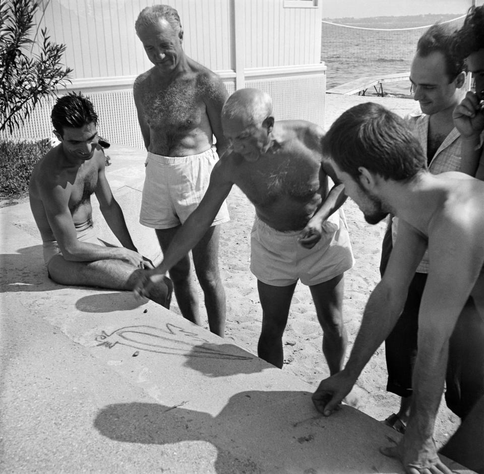 Pablo Picasso drawing a dove in chalk flanked by painters, Javier Vilato and Manuel Angeles Ortiz, in Golfe-Juan, 1950.