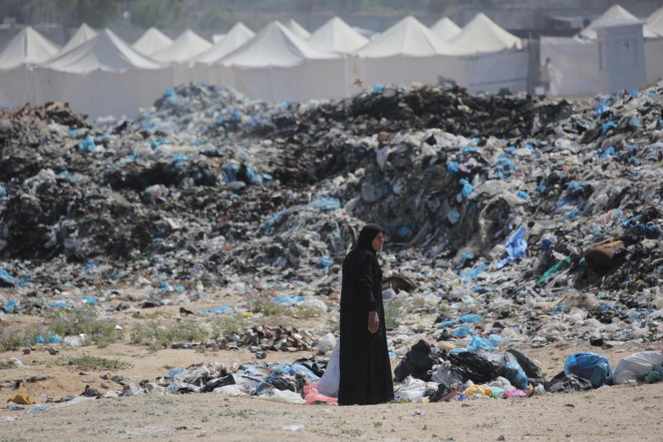 A woman salvages items from a waste dump along a tent displacement camp west of Nuseirat in the Gaza Strip on May 21, 2024.