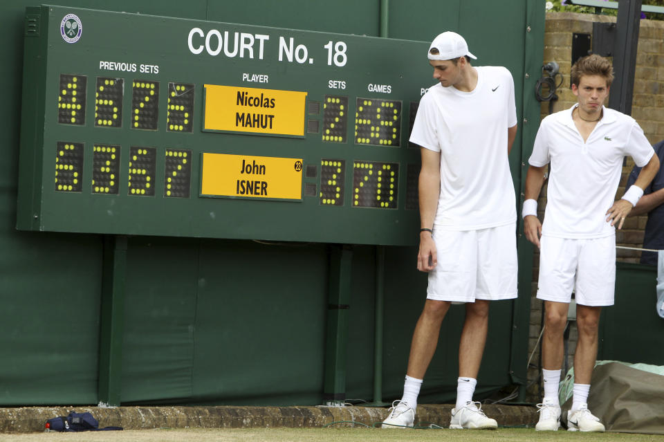 FILE - John Isner of the United States, left, and France's Nicolas Mahut pose for a photo next to the scoreboard following their epic men's singles match at the All England Lawn Tennis Championships at Wimbledon, June 24, 2010. Every so often, a debate bubbles up around whether it makes sense for men to keep playing best-of-five-set matches at Wimbledon and other Grand Slam tournaments. Consider Novak Djokovic a staunch advocate for keeping the format — at least in the latter stages of majors. (AP Photo/Alastair Grant, Pool, File)