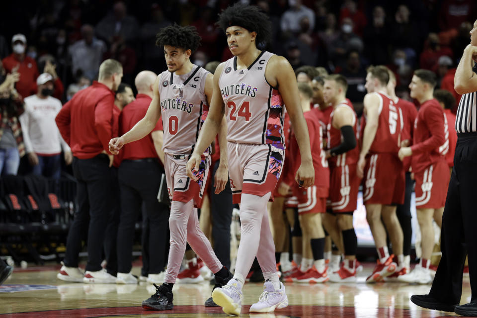 Rutgers forward Ron Harper Jr. (24) and guard Geo Baker (0) walk past the Wisconsin bench during the second half of an NCAA college basketball game Saturday, Feb. 26, 2022, in Piscataway, N.J. (AP Photo/Adam Hunger)