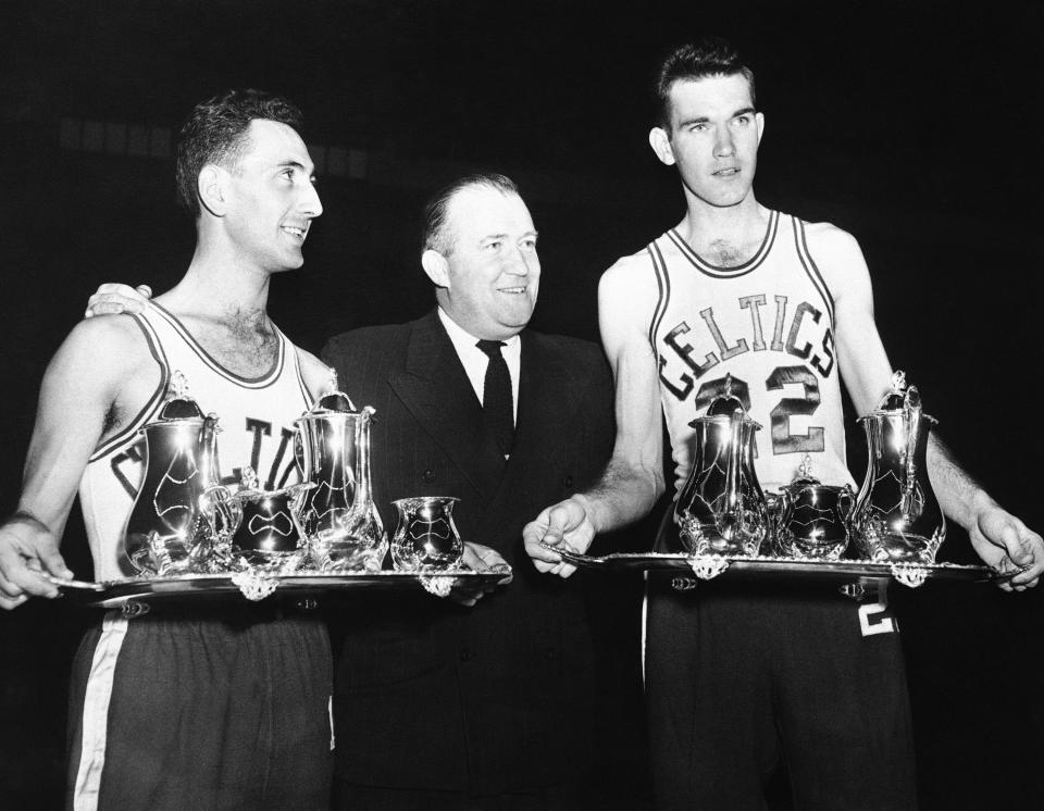 FILE - In this Jan. 16, 1952, file photo, Boston Celtics owner Walter Brown, center, presents Celtics' Bob Cousy, left, and Ed MacAuley sterling silver tea services on behalf of fans, teammates and Holy Cross and St. Louis University alumni in Boston. MacCauley starred with St. Louis University, and Cousy was an outstanding player with Holy Cross College. The players were honored before the Boston Minneapolis Lakers game at the Boston Garden. (AP Photo/Bill Chaplis, File)