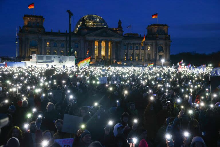 Los participantes iluminan con sus teléfonos móviles durante una manifestación contra el racismo y la extrema derecha frente al edificio del Reichstag en Berlín, Alemania, el 21 de enero de 2024. 