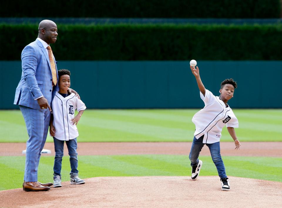 Former Detroit Tigers player Craig Monroe, left, with son Cannon, watches twin Collin throw out a ceremonial first pitch before a baseball game against the Kansas City Royals, Sunday, Aug. 11, 2019, in Detroit. Craig Monroe was honored with Tigers' Willie Horton African American Legacy Award during a pregame ceremony.