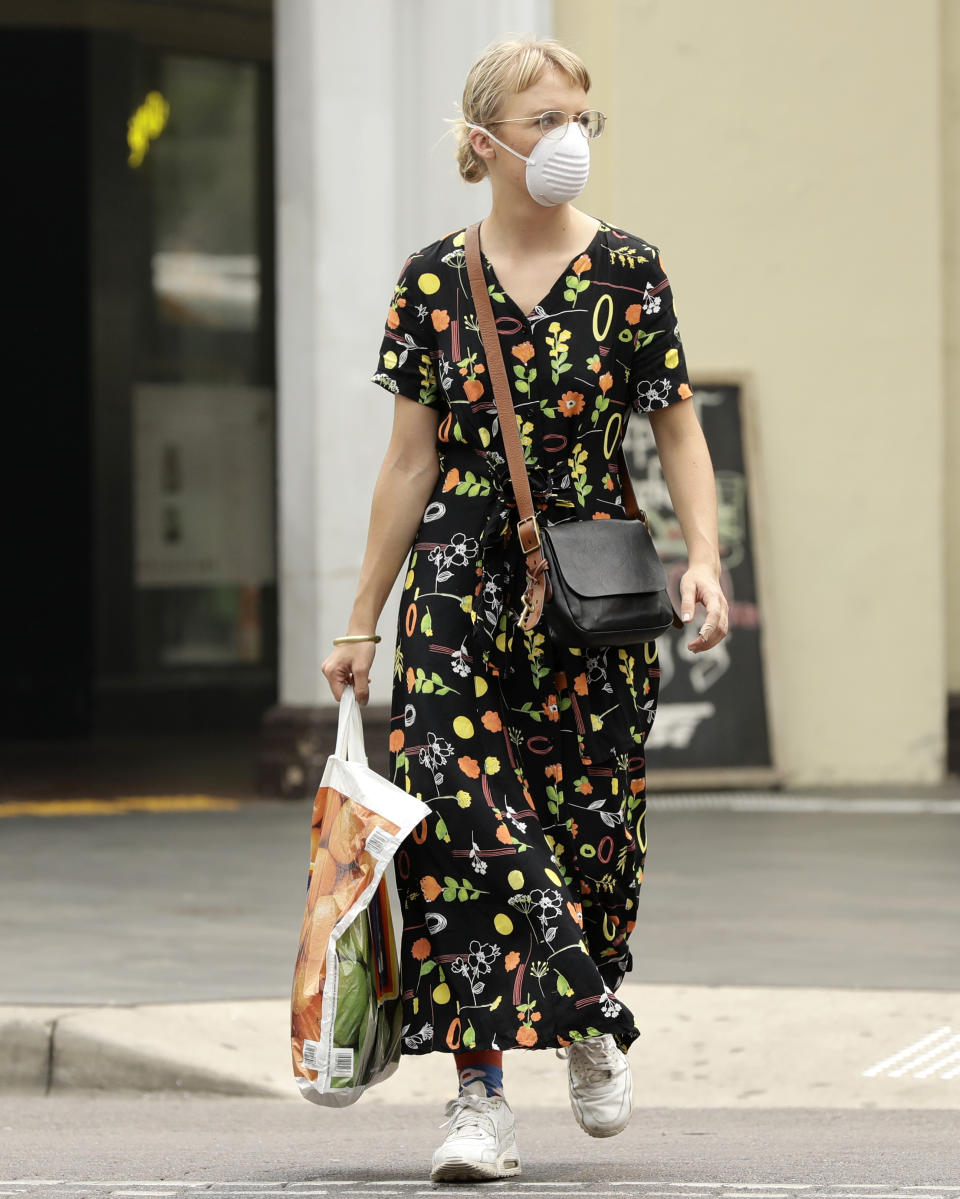 A pedestrian wears a mask as smoke shrouds the Australian capital of Canberra, Australia, Thursday, Jan. 2, 2020. Australia deployed military ships and aircraft to help communities ravaged by apocalyptic wildfires that destroyed homes and sent thousands of residents and holidaymakers fleeing to the shoreline. (AP Photo/Mark Baker)