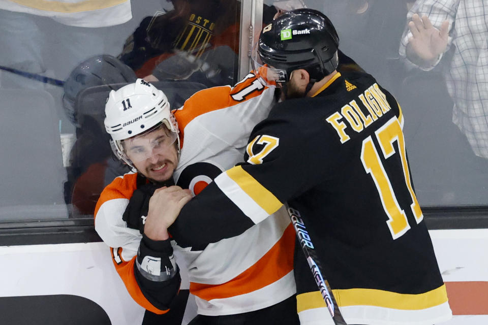 Philadelphia Flyers right wing Travis Konecny (11) and Bruins left wing Nick Foligno (17) fight along the boards during the second period of an NHL hockey game, Monday, Jan. 16, 2023, in Boston. (AP Photo/Mary Schwalm)