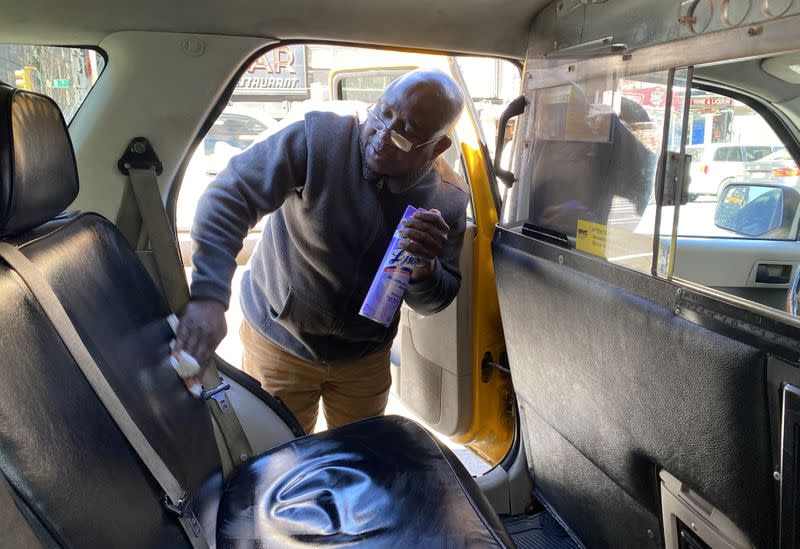 Yellow taxi cab driver Martin Oseseyi uses disinfectant while cleaning his cab amid the coronavirus outbreak in midtown Manhattan in New York City