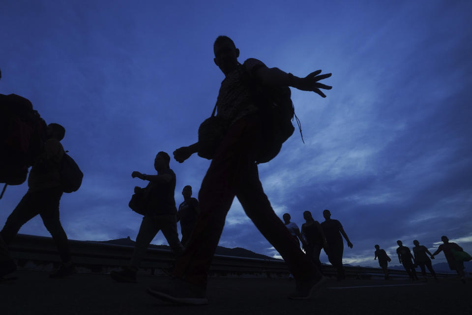 Migrants walk north on the highway toward the exit to Huixtla, Chiapas state, Mexico, at sunrise Thursday, June 9, 2022. The group left Tapachula on Monday, tired of waiting to normalize their status in a region with little work. (AP Photo/Marco Ugarte)