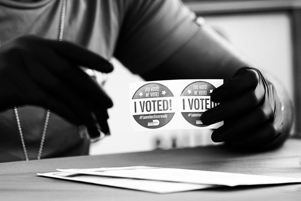 An election worker holds “I Voted” stickers as people drop off their ballots for the Nov. 3 general election at the Miami-Dade County Elections Department in October 2020.