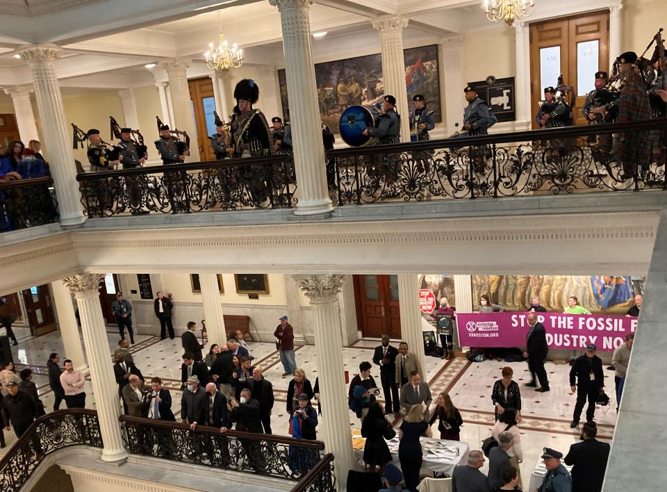 Climate activists set up signs opposing fossil fuel opposite the House Chambers doors in anticipation of Gov. Maura Healey's exit from her inauguration ceremony.