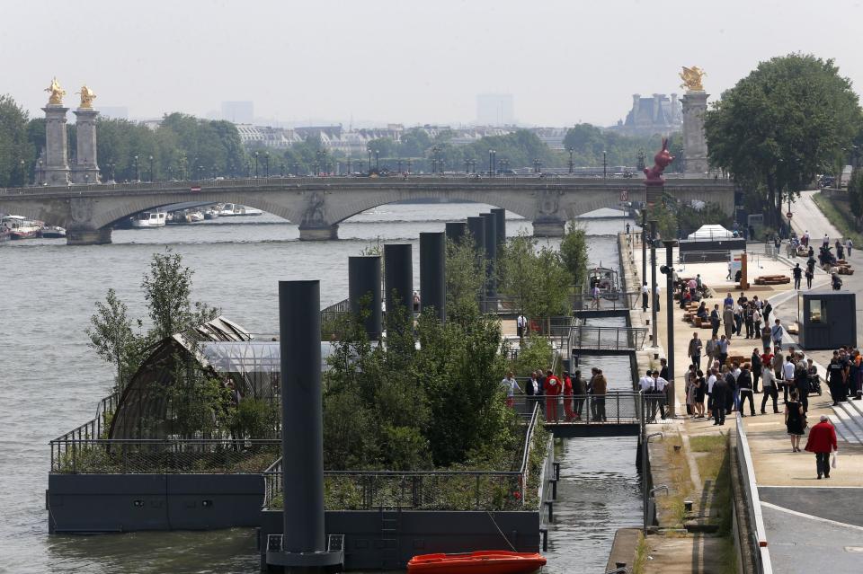 People stroll along the Left Bank of the Seine river where a new promenade has been inaugurated, Wednesday, June 19, 2013 in Paris. The 2.3 km (1.4 miles) walkway offers gardens, cafes, culture and sports activities. (AP Photo/Jacques Brinon)