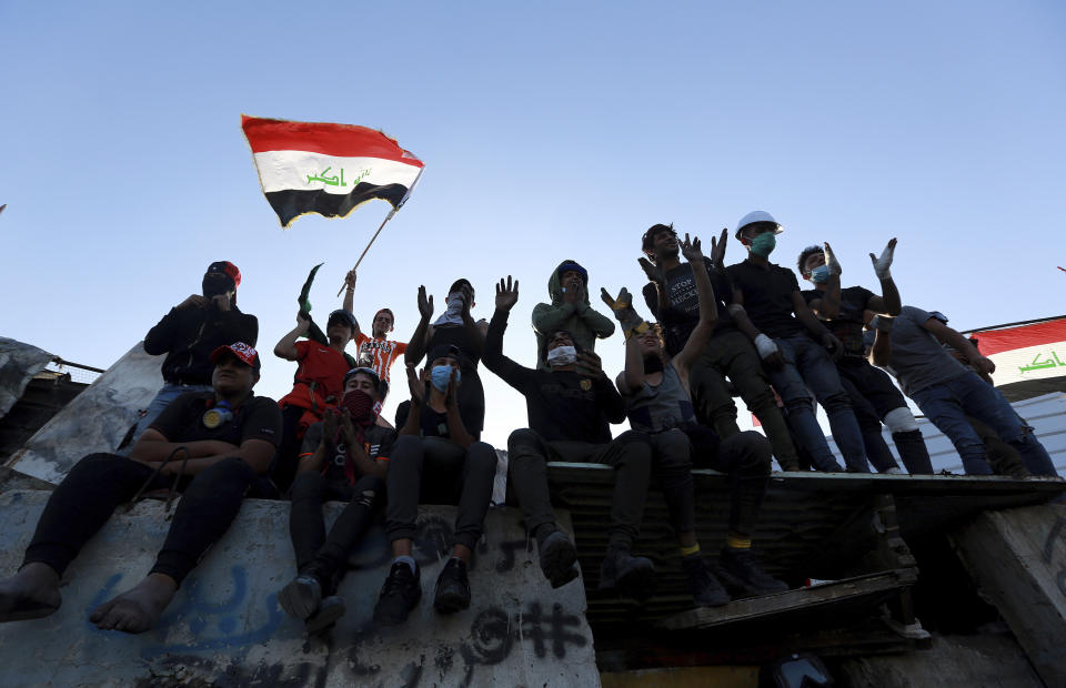 Protesters sit on a concrete wall erected by security forces to close a street leading to the Green Zone government areas, during clashes between Iraqi security forces and anti-government demonstrators in Baghdad, Iraq, Saturday, Nov. 16, 2019. (AP Photo/Hadi Mizban)