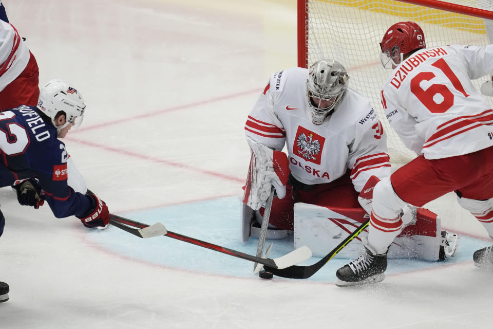 Poland's goalkeeper John Murray, center,makes a save in front of Unted States' Cole Caufield, left, during the preliminary round match between Poland and United States at the Ice Hockey World Championships in Ostrava, Czech Republic, Friday, May 17, 2024. (AP Photo/Darko Vojinovic)