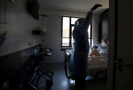 A physiotherapist from the Belgian Army works to exercise the breathing of a patient with COVID-19 at the St. Michiel Hospital in Brussels, Tuesday, Nov. 24, 2020. The Belgian military has been called into several hospitals and care homes to alleviate the stress on healthcare personnel. (AP Photo/Virginia Mayo)