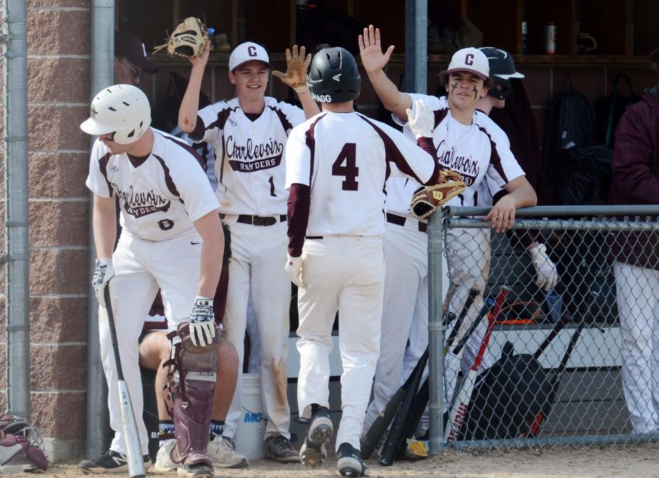 Charlevoix players in the dugout celebrate with teammate Patrick Sterrett (4) after he came around to score in game one.
