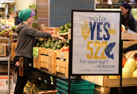 FILE PHOTO: An employee stocks produce near a sign supporting a ballot initiative in Washington state that would require labeling of foods containing genetically modified crops at the Central Co-op in Seattle, Washington October 29, 2013. REUTERS/Jason Redmond/File Photo