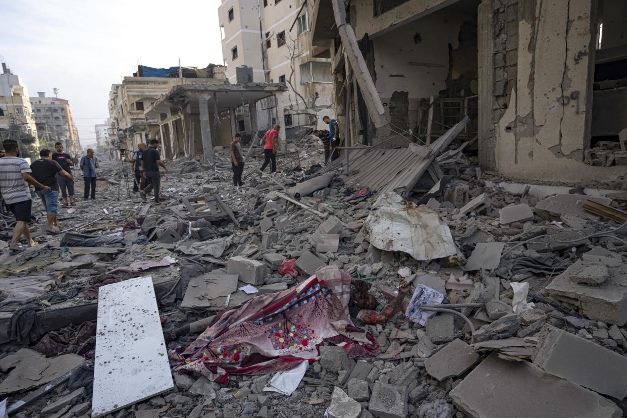 Palestinians stand among the destruction by Israeli bombing in Gaza City on Wednesday, Oct. 11, 2023. (AP Photo/Fatima Shbair)