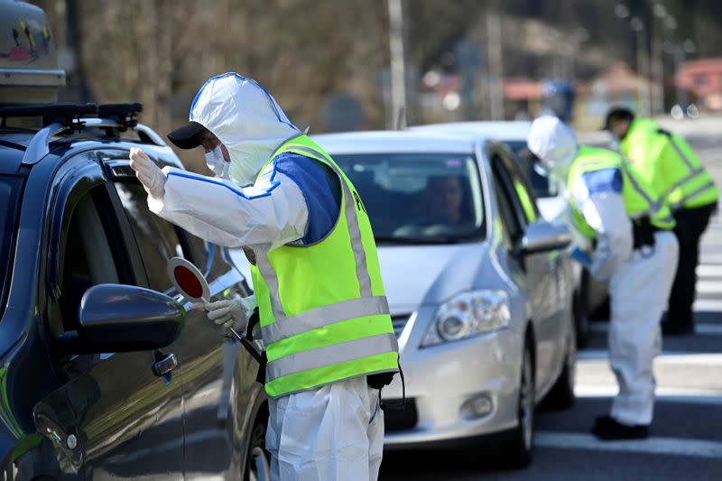 FILE PHOTO: Police officers in protective suits speak with people inside cars at the Slovak-Czech border in Drietoma crossing