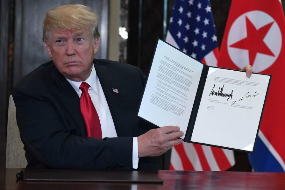 U.S. President Donald Trump holds up a document signed by him and North Korea's leader Kim Jong Un following their historic US-North Korea summit, at the Capella Hotel on Sentosa island in Singapore on June 12, 2018.