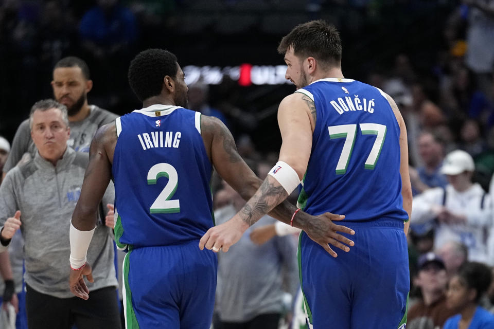 Dallas Mavericks' Kyrie Irving (2) and Luka Doncic (77) talk as they walk to the bench during a time out in the second half of an NBA basketball game against the Philadelphia 76ers, Thursday, March 2, 2023, in Dallas. (AP Photo/Tony Gutierrez)
