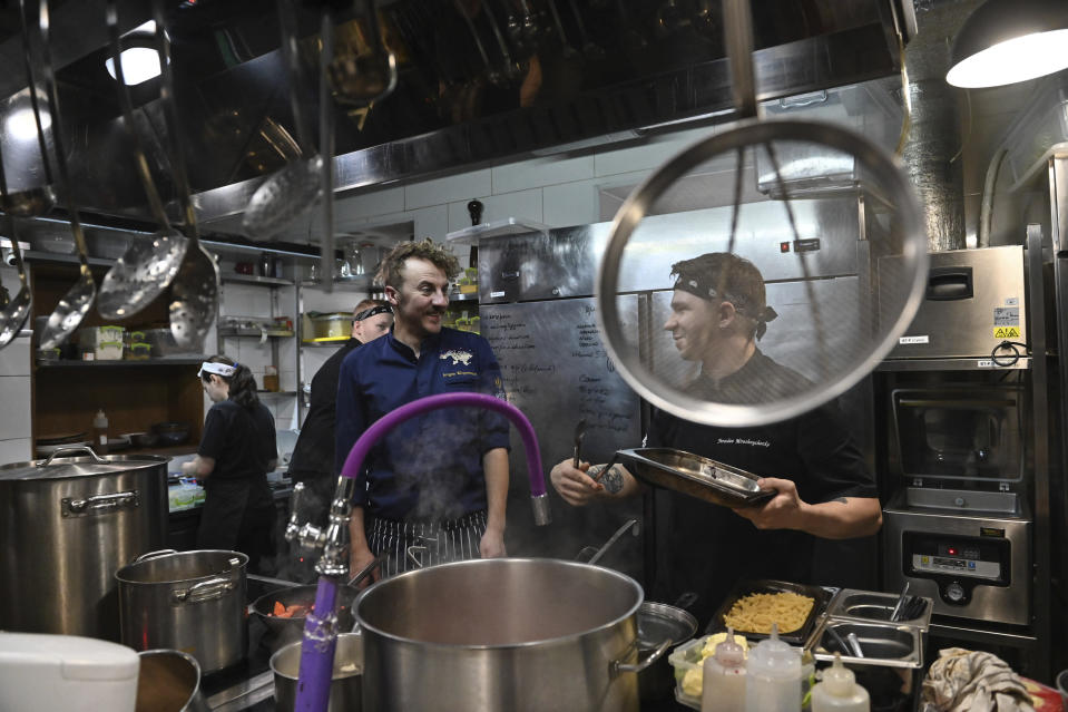 Ukrainian chef Ievgen Klopotenko, center, appears in the kitchen of his restaurant, 100 Rokiv Tomu Vpered (100 Years Ago Ahead), in Kyiv on Monday, Feb. 6, 2023. Klopotenko has been outspoken during the Russian invasion in promoting national dishes, especially borsch, as a way of establishing a definite identity for Ukraine. (AP Photo/Chris Warde-Jones)