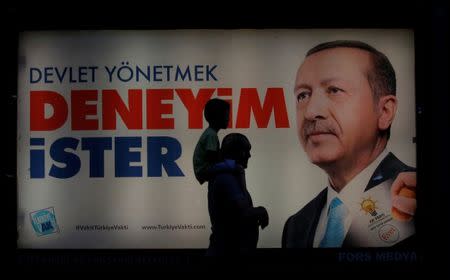 People walk past an election poster for Turkey's President Tayyip Erdogan in Istanbul, Turkey, June 14, 2018. The poster reads, "Governing requires experience". REUTERS/Huseyin Aldemir