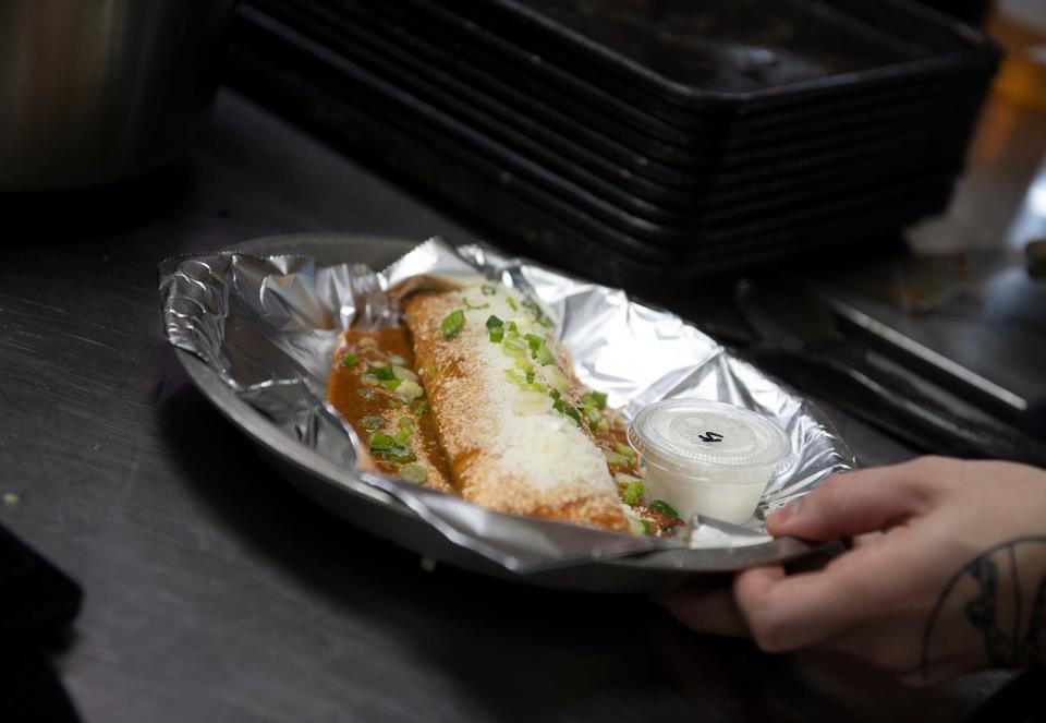 Taco Tontos employee Noah Gfell takes a finished enchilada order out to the dining area of the Kent restaurant.