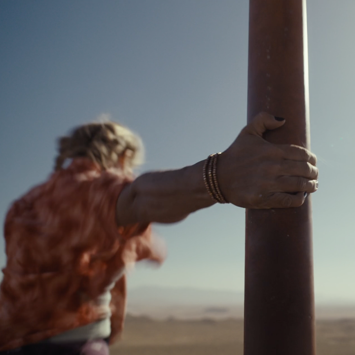 A hand wearing bracelets clings to a rusty metal pole