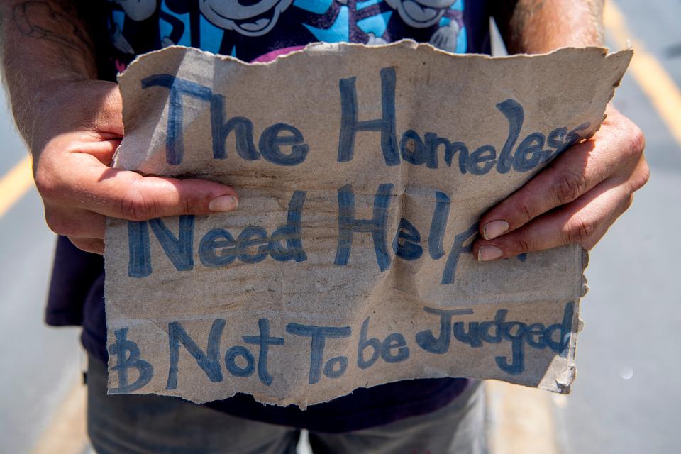 Sean Alcock, who is homeless, stands in the middle of Patton Ave. asking for help from motorists August 4, 2023.