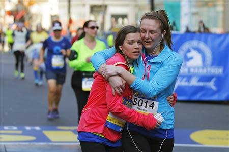 Remy Lawler (L), 2013 Boston Marathon bombing survivor, gets a hug from Hannah Wiggin after crossing the marathon finish line while running the Boston Athletic Association's 5K race in Boston, Massachusetts April 19, 2014. REUTERS/Brian Snyder