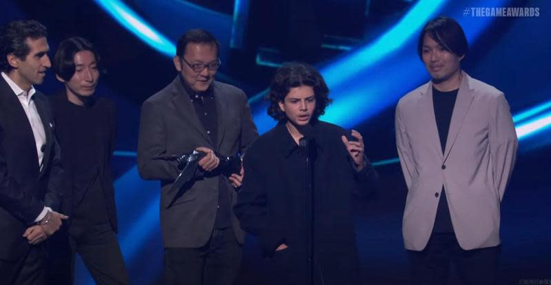 《艾爾登法環》獲得年度最佳遊戲殊榮，不過在頒獎典禮中，突然有位黑衣少年（右2）亂入其中還搶走麥克風。（翻攝自The Game Awards 2022 Live）