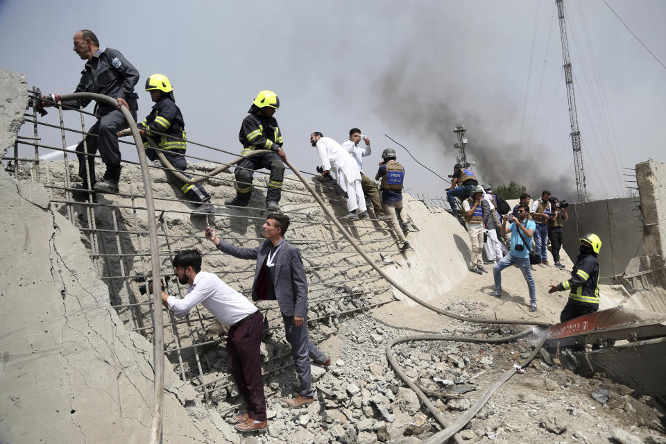 Afghan firefighters and journalists work at the site of Monday's suicide bomb attack in Kabul, Afghanistan, Tuesday, Sept. 3, 2019. The attack occurred late Monday near the the Green Village, home to several international organizations and guesthouses. (AP Photo/Rahmat Gul)