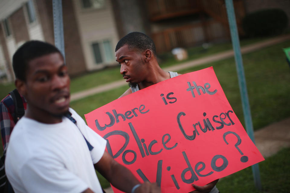 FERGUSON, MO - AUGUST 11: Demonstrators protest next to the spot where 18-year-old Michael Brown was shot by police on Saturday on August 11, 2014 in Ferguson, Missouri. Police responded with tear gas and rubber bullets as residents and their supporters protested the shooting by police of an unarmed black teenager named Michael Brown who was killed Saturday in this suburban St. Louis community. Yesterday 32 arrests were made after protests turned into rioting and looting in Ferguson.  (Photo by Scott Olson/Getty Images)